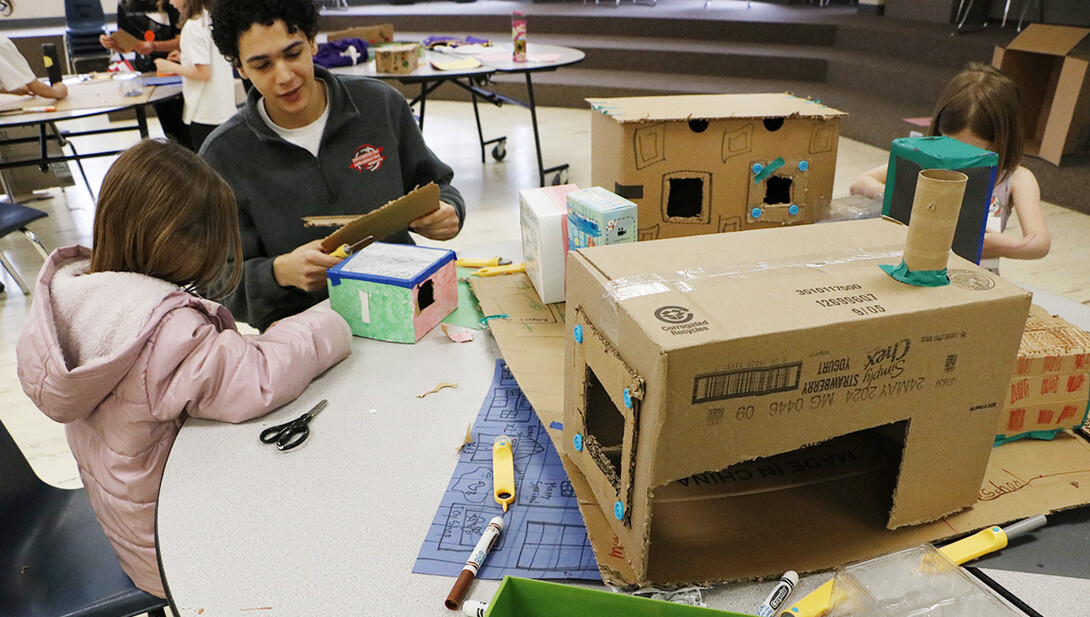 Honors student and Engineering Ambassador Adam Algahimi helps a student at Calvert Elementary work on her CityBuild model.