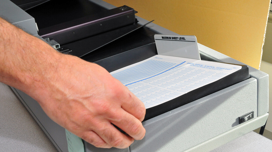 Ben Lass, an exam services coordinator, loads bubble sheets into a test score machine in UNL's Exam Services office.