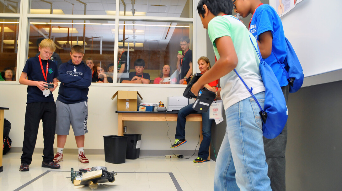 Sumo bot teams from (left) Oklahoma and Connecticut battle inside a Jorgensen Hall laboratory. The event is won by pushing an opposing robot out of the marked ring.