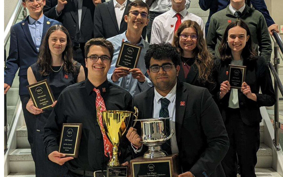 Image of Nebraska Debate Team members holding trophies and awards earned at the national competition.