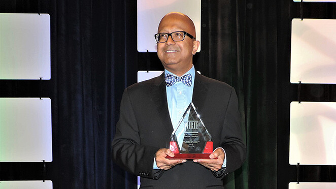 Dipra Jha grasps his ICHRIE award for innovation in teaching.