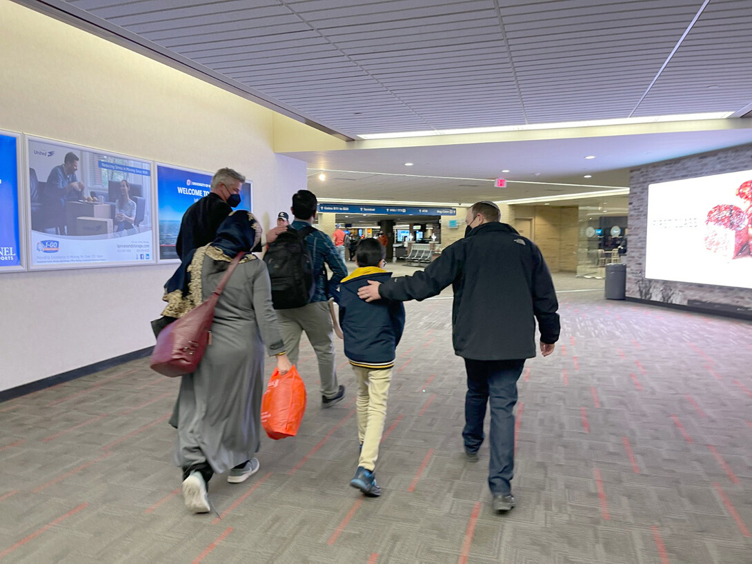 Scott Kleeb (left) and Ari Kohen (right) escort Farooq, his wife and two children through Omaha's Eppley Airport Jan. 4.