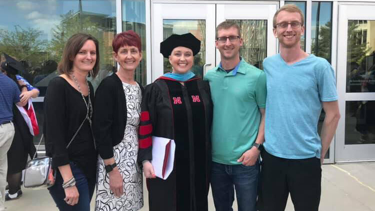 Nicole Frerichs (center) poses outside Pinnacle Bank Arena with family after receiving her doctoral degree in 2019.