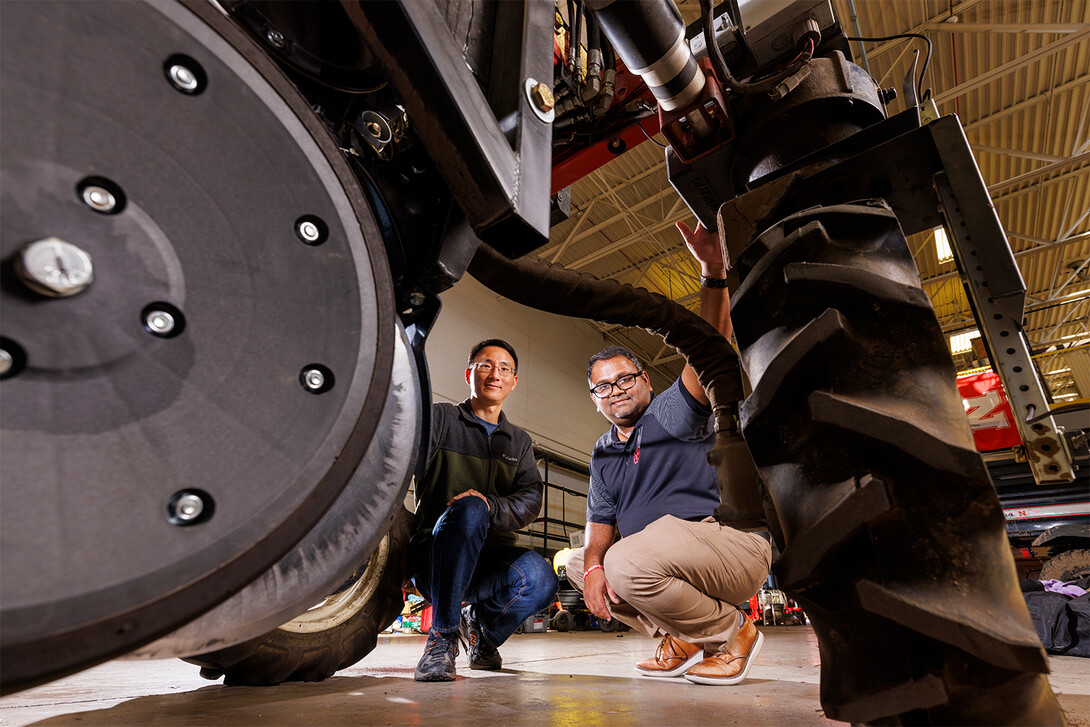 Yufeng Ge and Santosh Pitla squat beneath Flex-Ro, an autonomous robotic planter