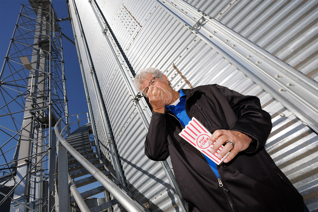 Norm Krug eating popcorn next to grain bin