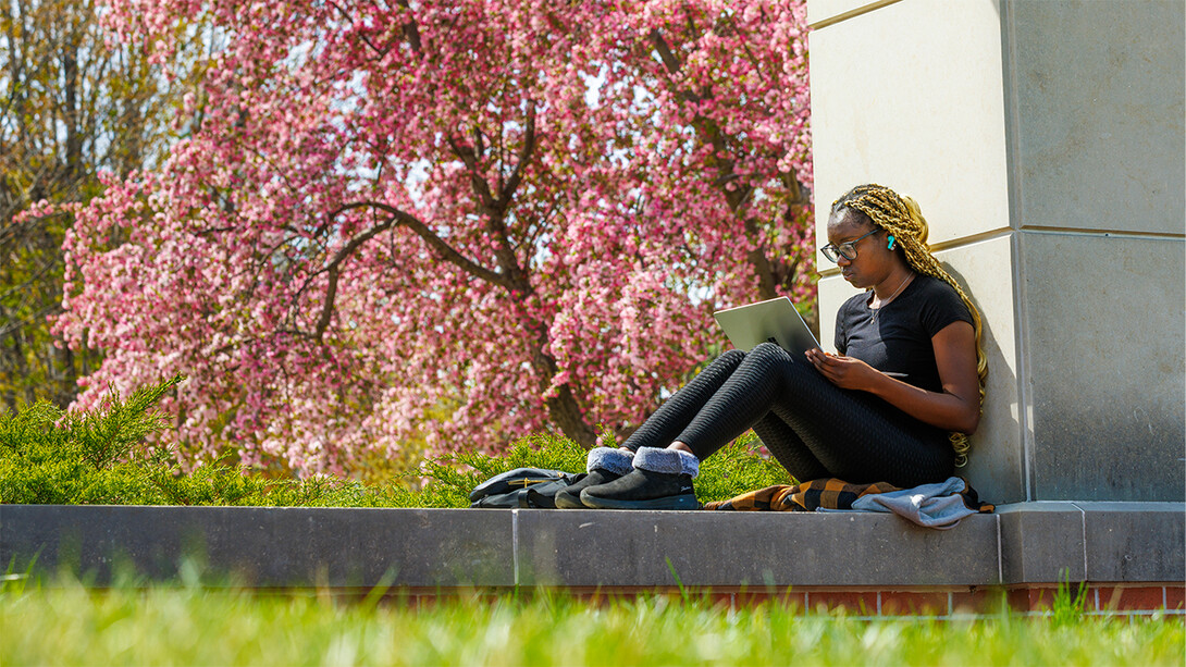 Maryam Ajibola studies next to an eastern redbud tree