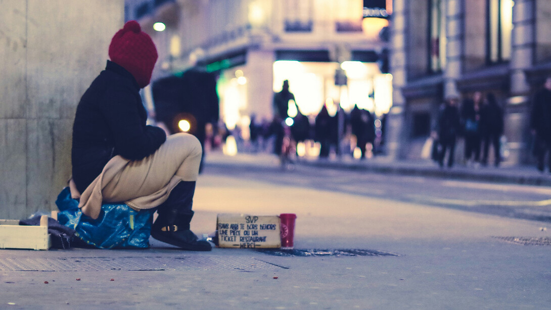 Homeless individual sitting on a deserted street.