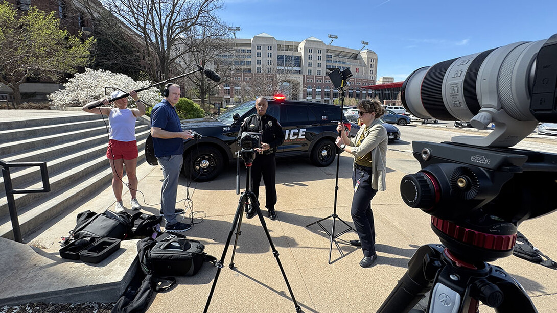 People stand in front of a setup of video cameras in front of Memorial Stadium.