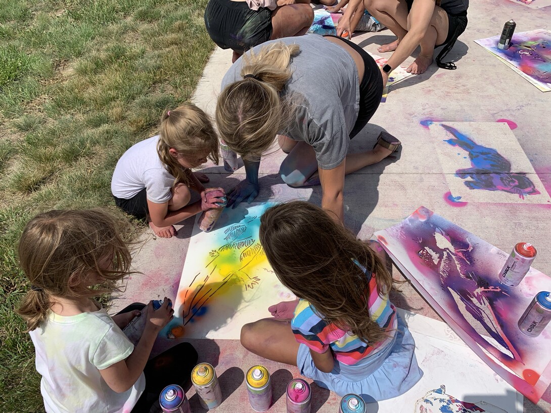 Students from the Alliance Recreation Center create spray chalk animals as part of the Stay Wild community arts project, led by Associate Professor of Art Sandra Williams.