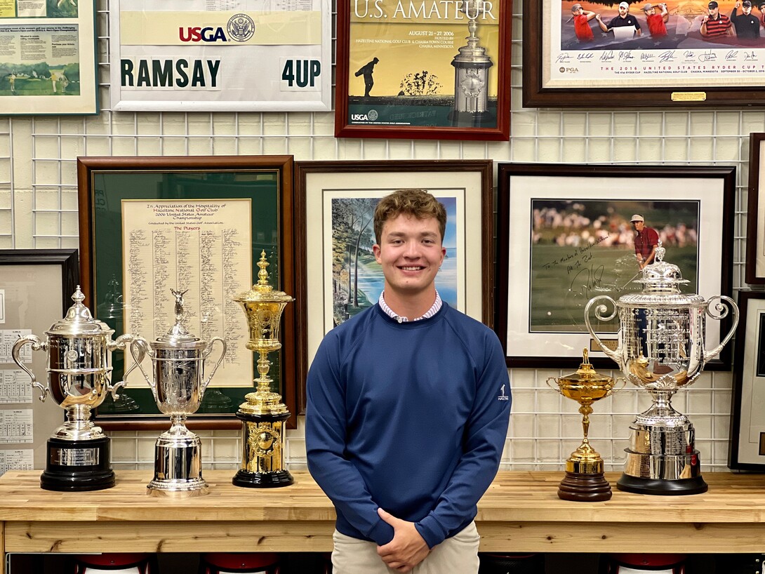 Koby Head stands in front of trophies from tournaments hosted at Hazeltine National Golf Club. Head gained career experience through a 16-week internship at the club..