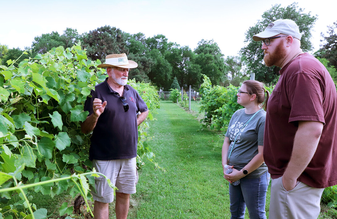 Professor Paul Read discusses wine grape research at the July 2 viticulture tailgate with attendees Megan and Sean Cox from Omaha in the University of Nebraska–Lincoln East Campus vineyard.