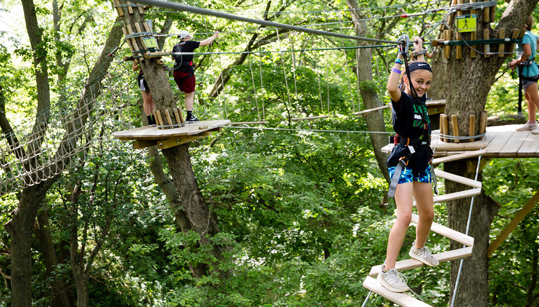 A young visitor completes the GoApe ropes course high in the trees at Mahoney State Park.