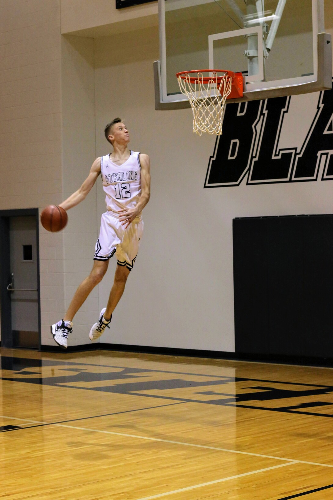 Tyus Wilson jumps for a dunk on a basketball court in Sterling, Kansas.