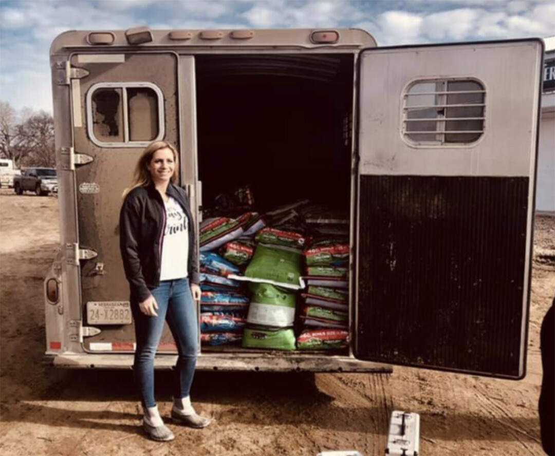 Katelyn Petersen stands next to a horse trailer loaded with items she collected for flood victims.