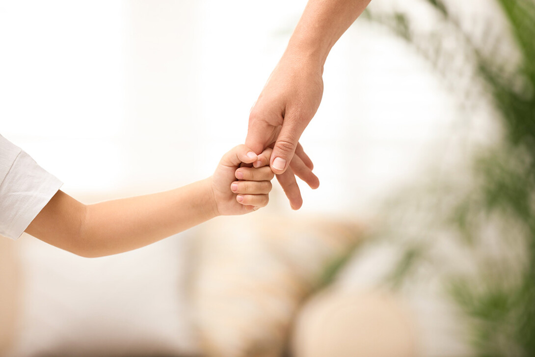 A parent holds a child's hand.