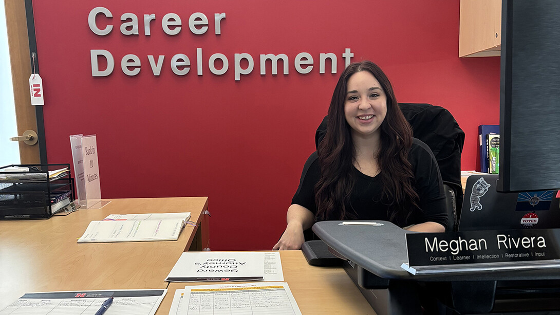 Meghan Rivera sitting at her desk in a black sweater in front of a Career Development sign.