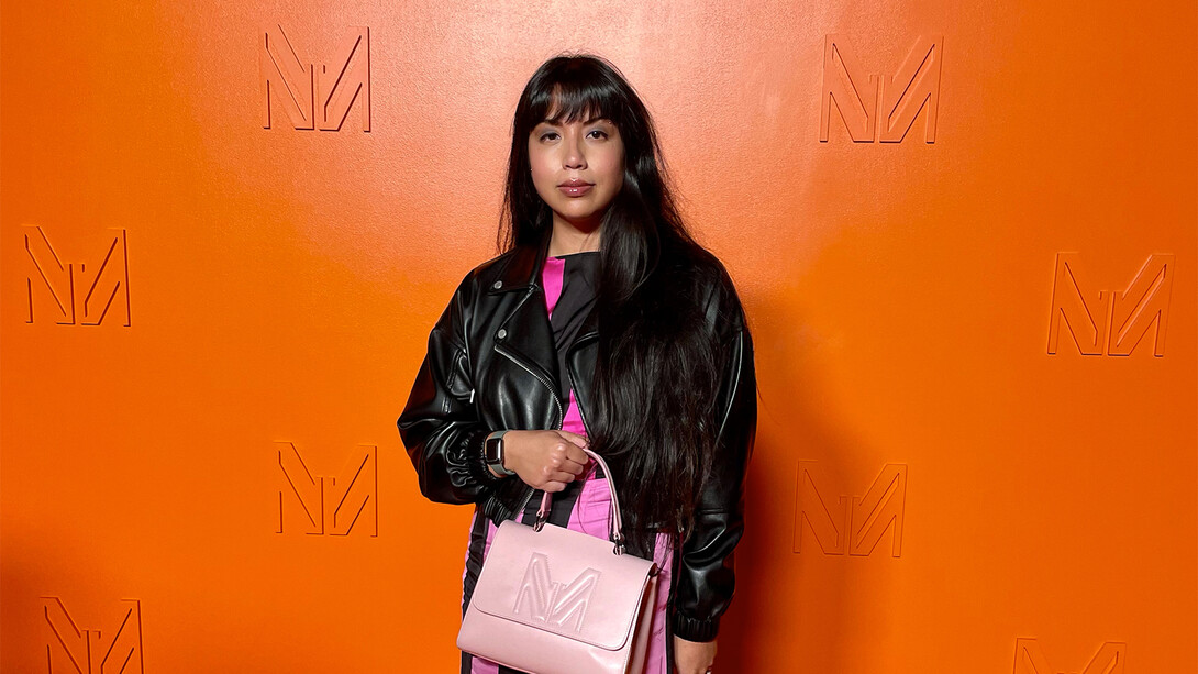 Mekita Rivas poses in front of an orange background.
