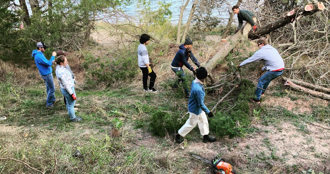 Chaining and dragging out trees, students prep the site at the Cedar Point Biological Station for a from scratch build.