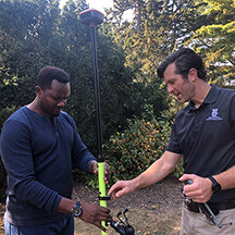 Samuel Nshutiyayesu (left) and Daniel Uden (right) demonstrate GPS equipment outside.