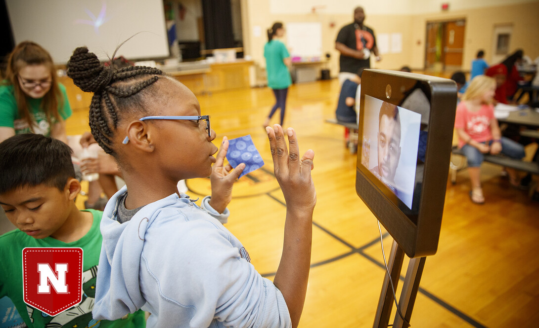 Ani'a Morris-Gordon interacts with Soham Patel, a UNL computer science major, who is using Beam technology to remote teach the class about nano technology and nano treated fabrics.