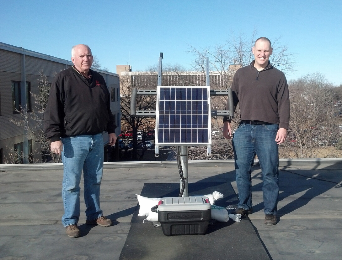 Rick Perk (left), assistant geologist, and Brian Wardlow, director of CALMIT and associate professor, stand with the PhenoCam on the roof of Hardin Hall. The camera is being moved to Nine Mile Prairie as part of a survey of North American landscapes.