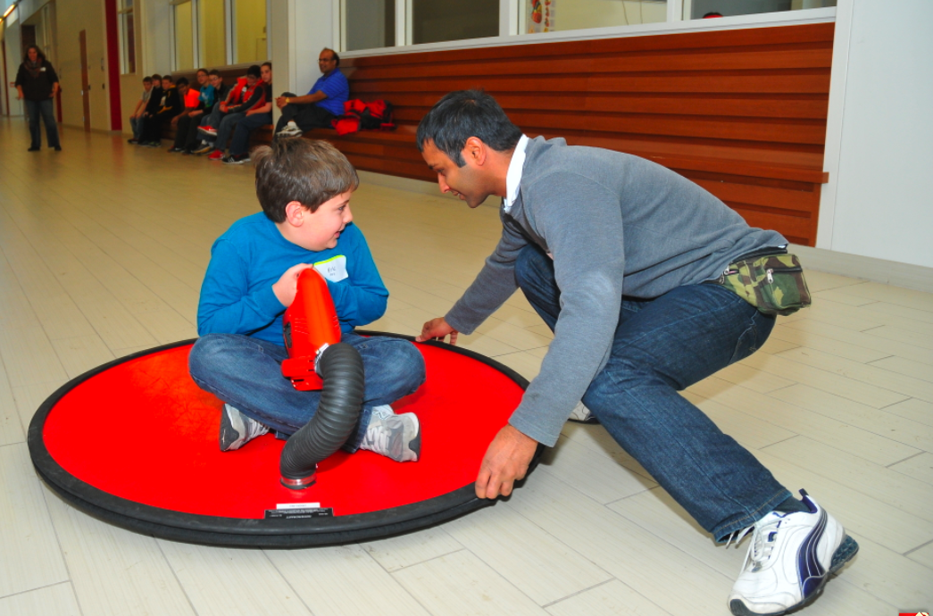 Om Goit (right), a UNL graduate student, helps a Lincoln Public Schools fifth grader ride a hover craft during Saturday Science.