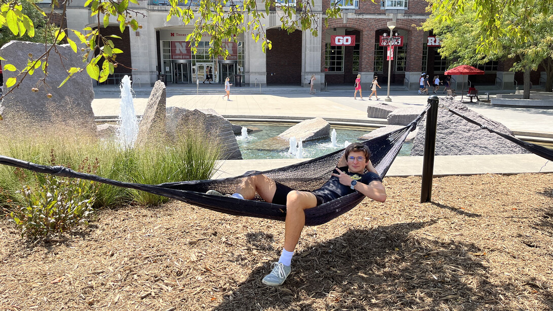 Bishop Placke, of Grand Island, Nebraska, throws up a peace sign as he relaxes in a hammock outside Nebraska Union. 