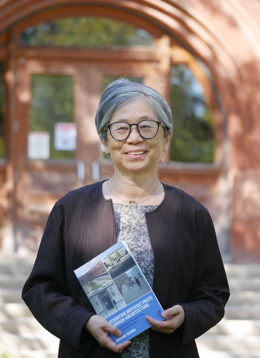 Rumiko Handa poses with her new book "Presenting Difficult Pasts Through Architecture: Converting National Socialist Sites to Documentation Centers"