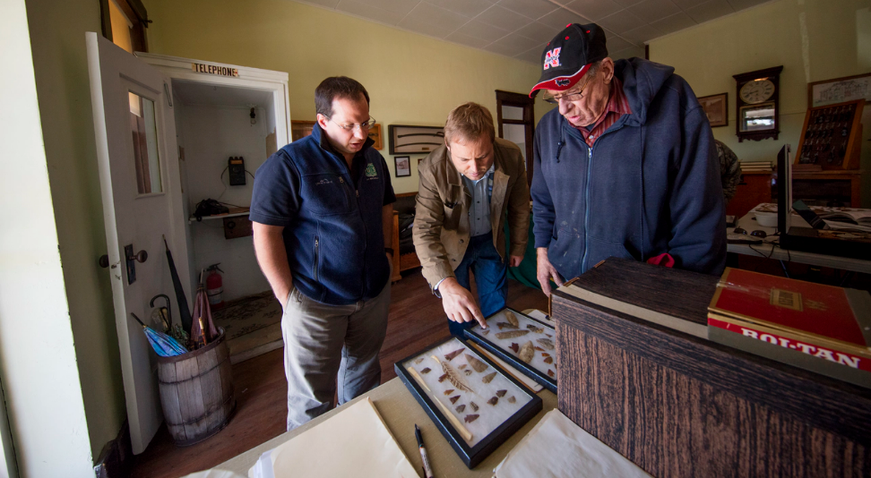 Dennis Kuhnel (from left) and Matt Douglass examine a collection brought in by John Furrow during an Oct. 7, 2016 Artifacts Roadshow in Mullen, Neb.