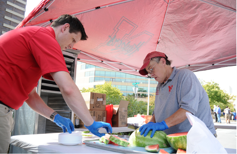 Tony Rathgeber and Dodie Fearing cut watermelon for the all-university picnic.