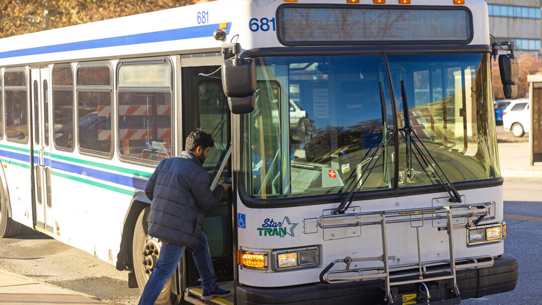 A man boards a white StarTran bus near campus.