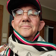Head shot of David Torquati with a scarf decorated with the colors of the Italian flag around his neck.