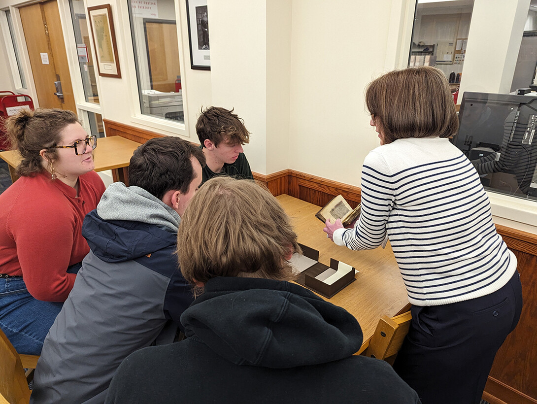 A woman shows a medieval book to students