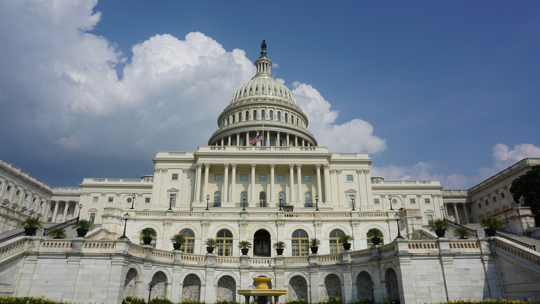 Photo of the U.S. Capitol building with blue sky and clouds in the background.