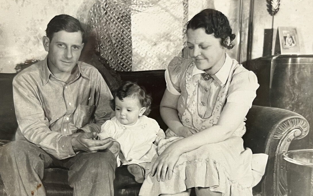 Photo of Michelle Waite's grandfather, mother (as a baby) and grandmother in a living room sitting on a couch.