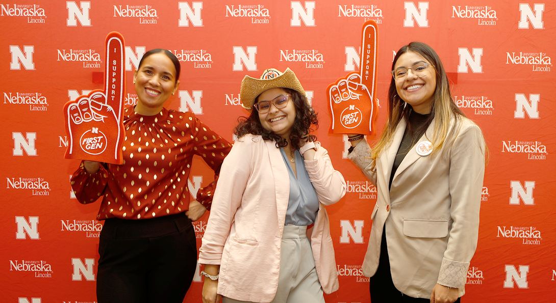 Three first-generation Huskers standing in front of a red and white wall.