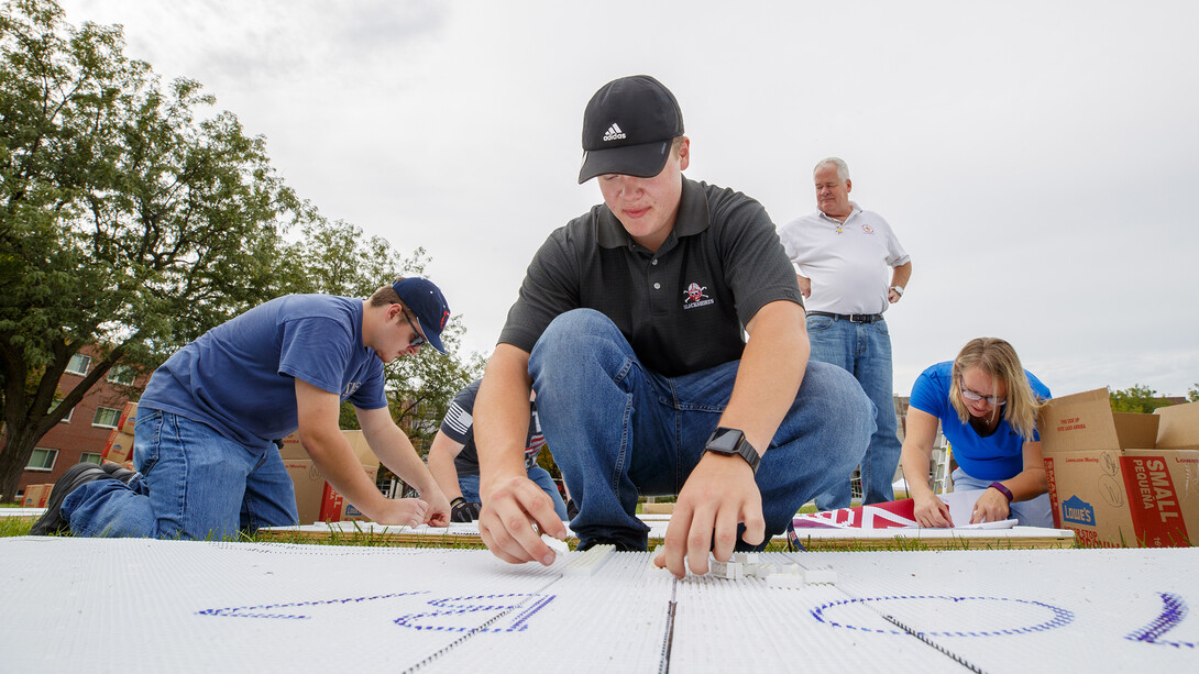 Husker John Lang starts placing white plastic bricks on the Nebraska "N" mosaic on Aug. 31.