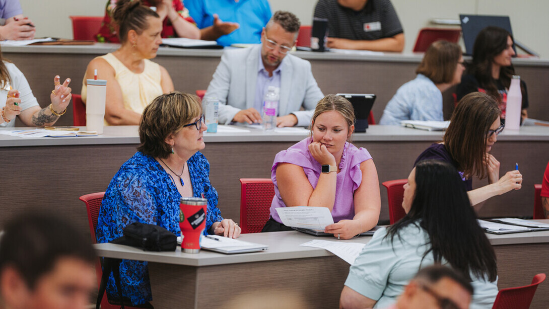 Faculty and staff are seated in an auditorium during NRICH sessions.