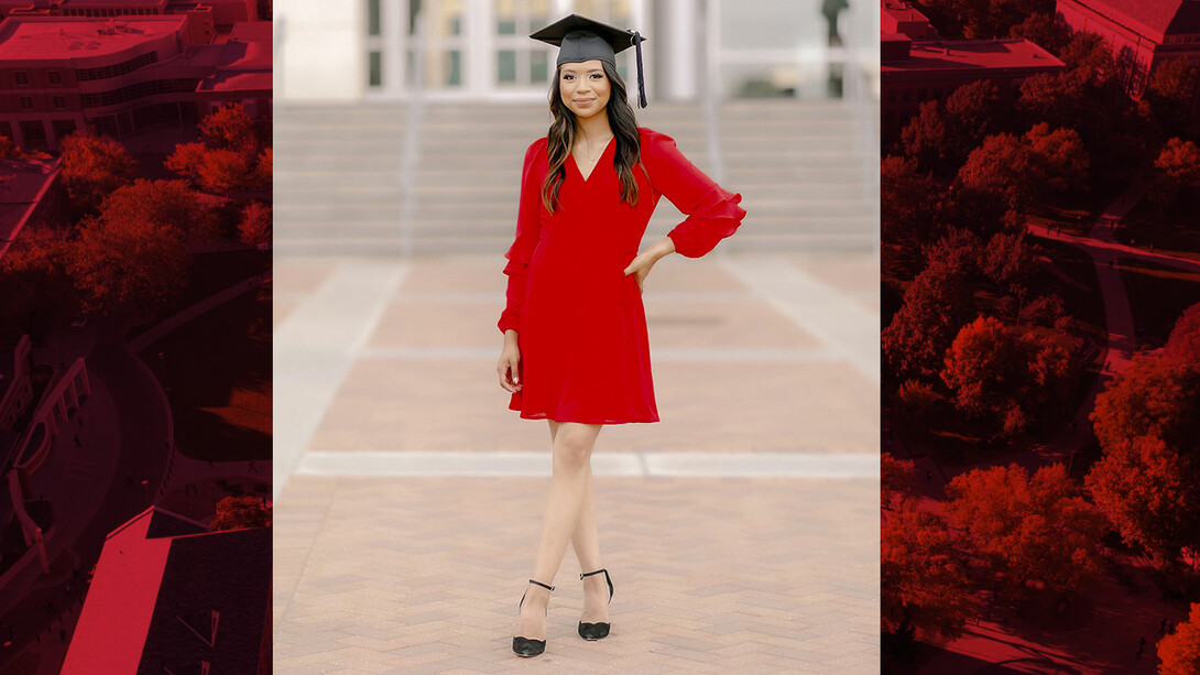 Carolina Saquiche Dominguez stands on bricks outside of Memorial Stadium wearing her mortar board.