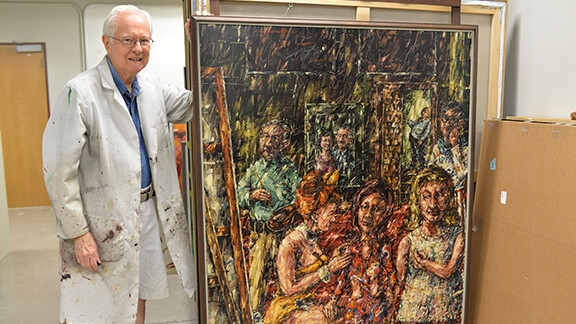 Dan Howard, professor emeritus of art, poses with one of his paintings in Richards Hall.