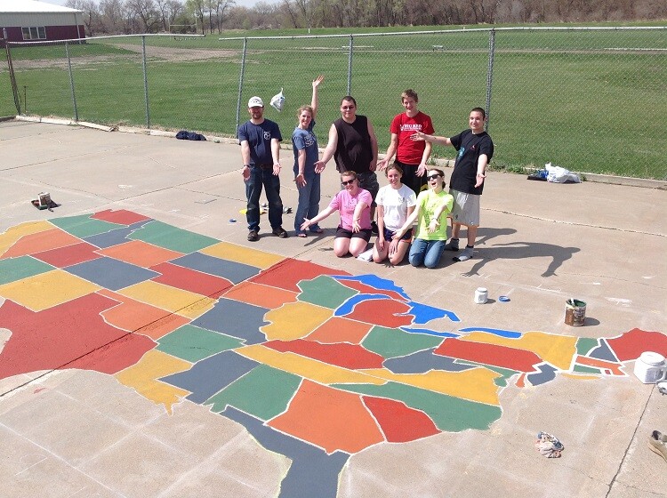 UNL students who are part of the Geography Student Organization pose by the nearly complete U.S. map painted on a Scribner-Snyder Community Schools playground.