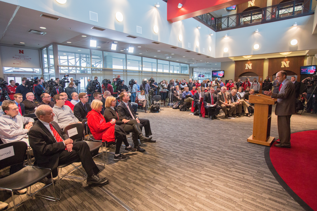 Administrators, staff, student-athletes and members of the media listen to Husker head coach Mike Riley's introductory news conference. 