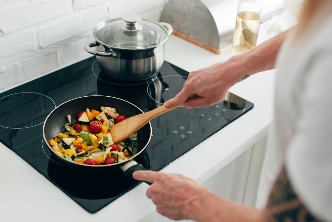 Colorful vegetables are being sautéed in a skillet.