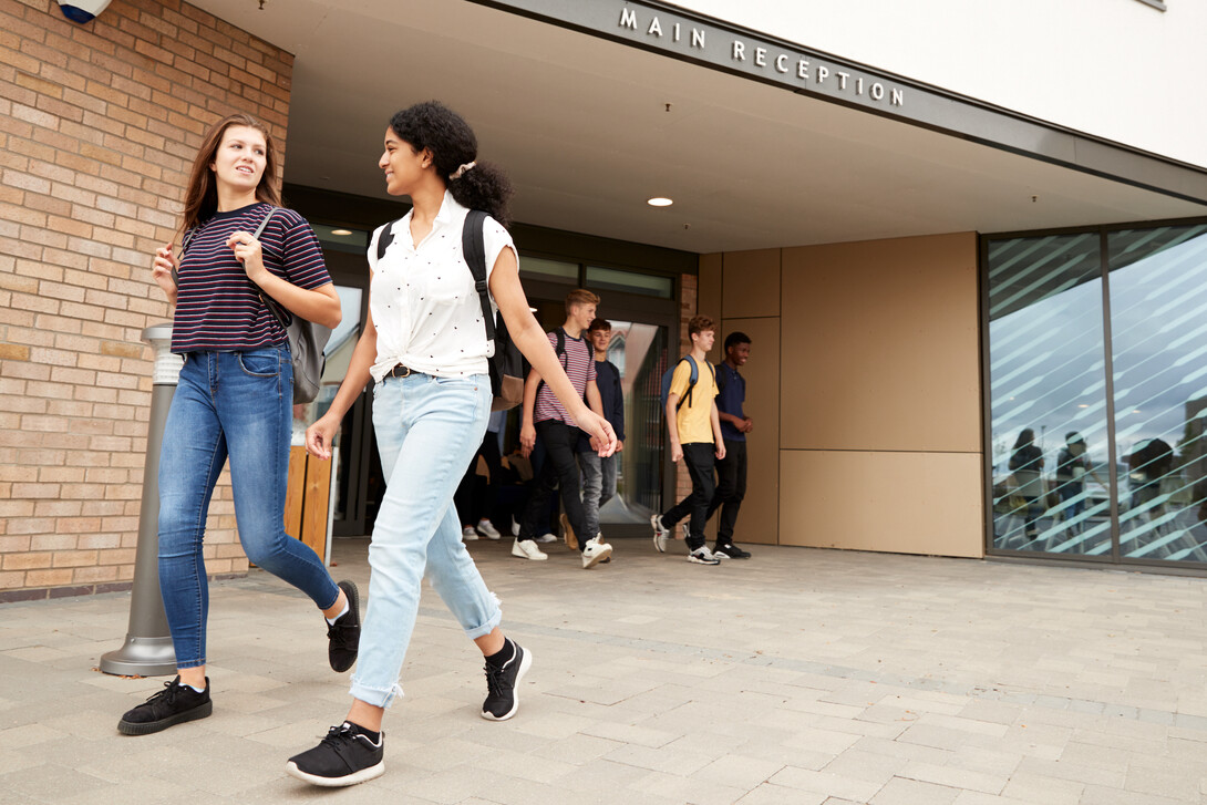 Students walk out of a school building.