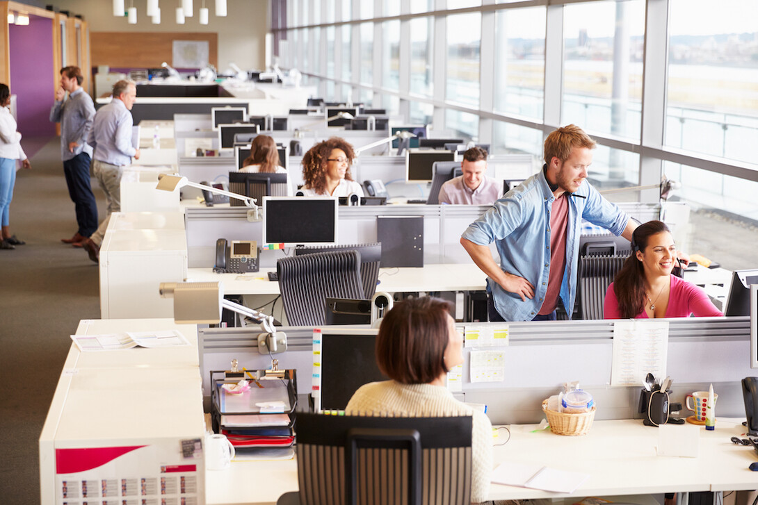 Casually dressed colleagues talking in an open plan office