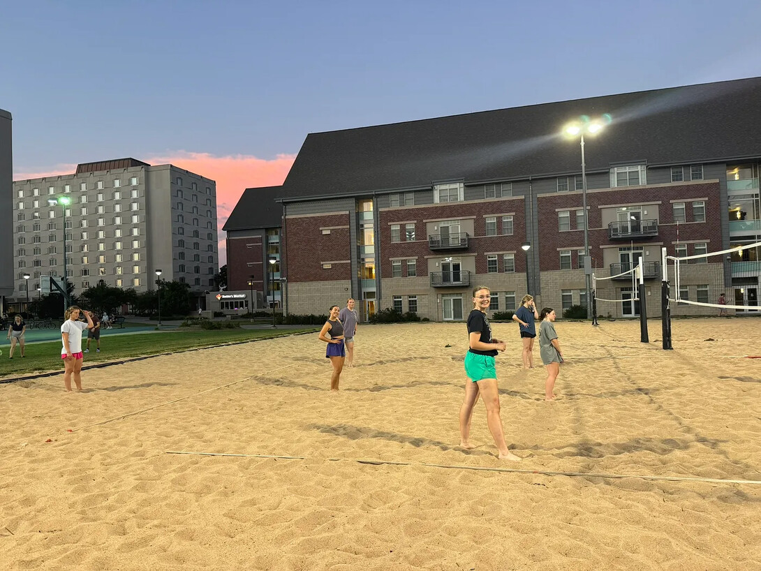 Students playing sand volleyball outdoors.