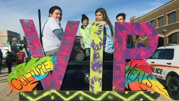 Students on a VIP, culture heals float from a parade.