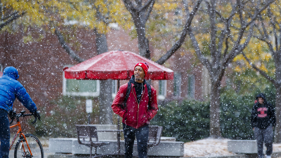 Snow falls as a student walks through the Nebraska's Union's Memorial Plaza. [University Communication]