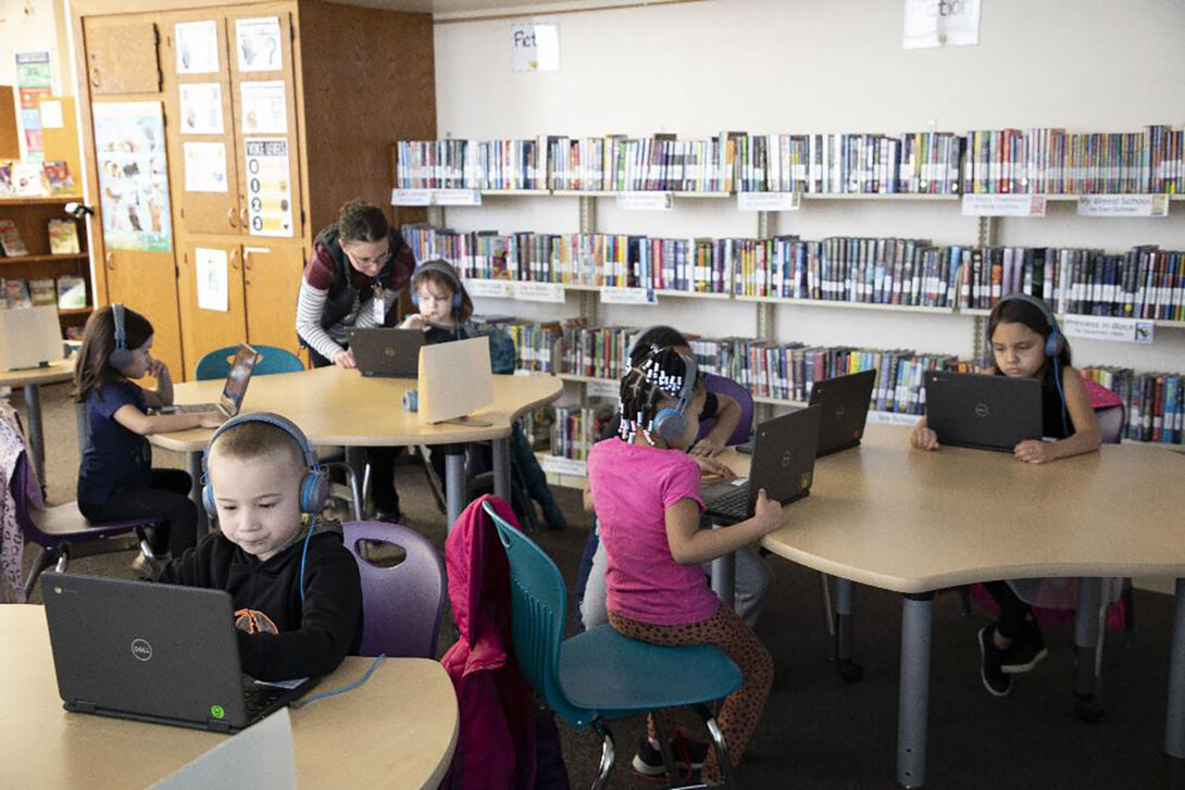 Elementary students work at laptops on coding skills