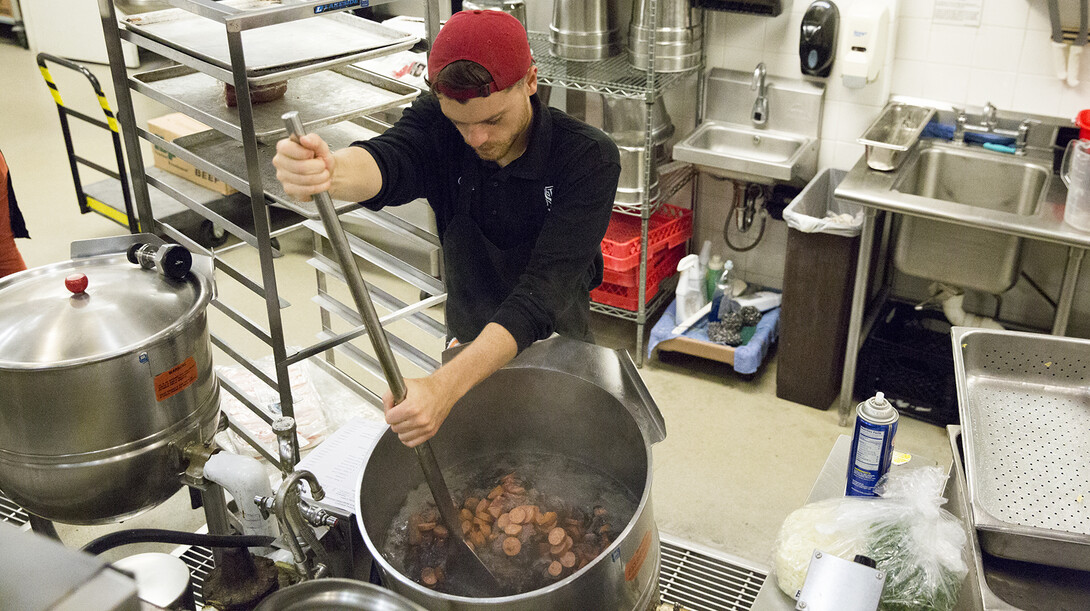 Chris Browne, a dining service associate in Selleck Hall, stirs Andouille sausage into a kettle of Brazilian feijoada. Requested by students, the dish is a mix of black beans and six different meats and is regularly served at UNL's Selleck Hall.